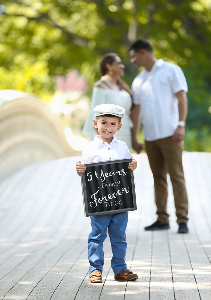 Couple celebrating their anniversary with their young son holding a sign