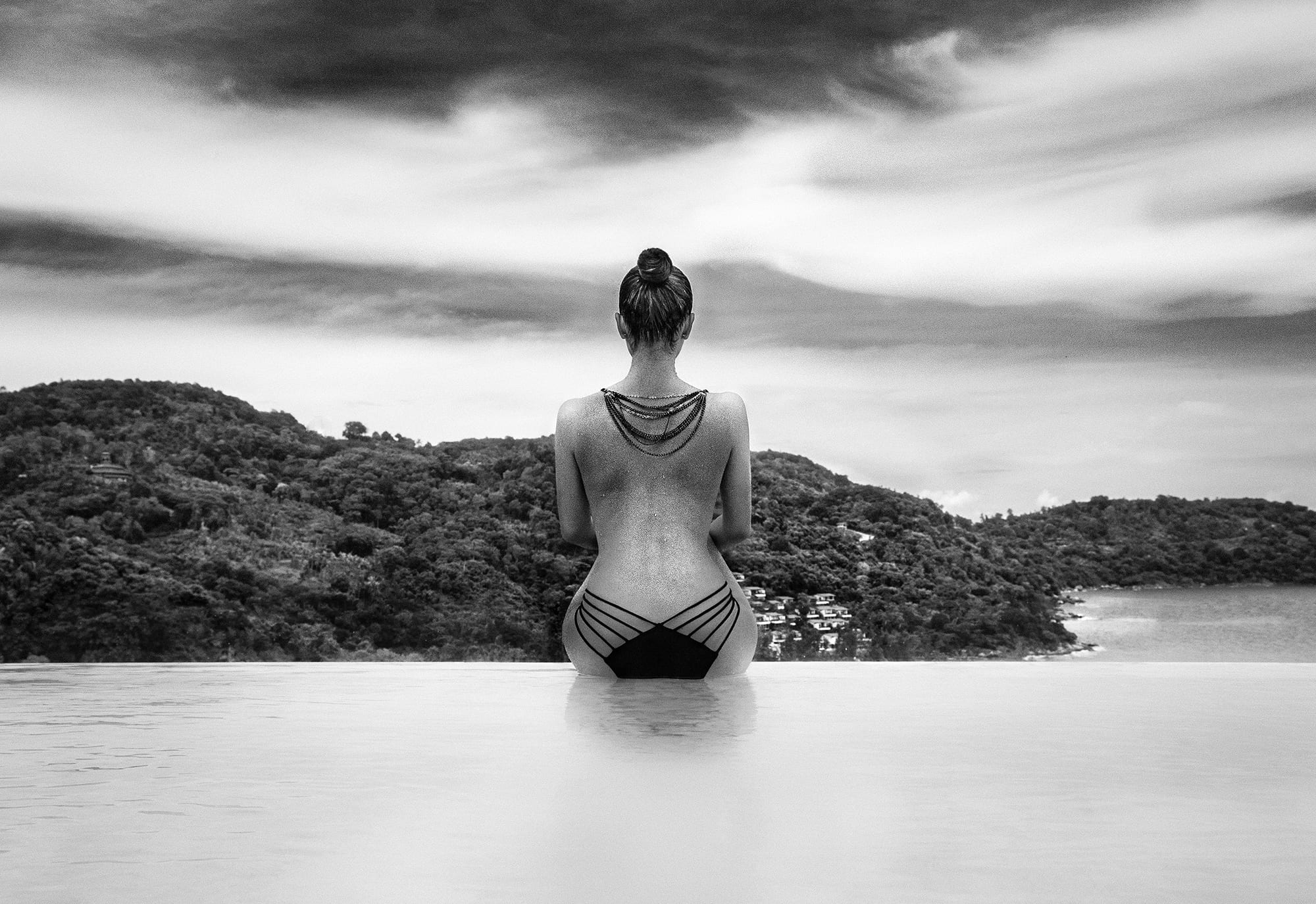 woman from behind in water facing rocks moody artistic portrait nature